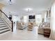 Open concept living room with stairs, neutral sofas, and modern decor at 8635 Tallfield Ave, Orlando, FL 32832