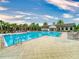 Community pool with sun loungers, palm trees, and a clubhouse, ideal for relaxation and recreation at 8635 Tallfield Ave, Orlando, FL 32832