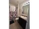 Well-lit bathroom with a shower and patterned shower curtain, complemented by a modern vanity at 1895 Hickory Bluff Rd, Kissimmee, FL 34744