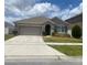 Charming single-story home featuring a well-maintained lawn and a two-car garage on a sunny day at 1895 Hickory Bluff Rd, Kissimmee, FL 34744
