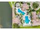 Aerial view of a resort-style community pool with tiled rooftops, landscaping, sun loungers, umbrellas, and green lawns at 1110 Terralago Way, Kissimmee, FL 34746