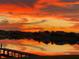 Scenic lake view with a dock reflecting vibrant orange and yellow colors from the sunset and neighborhood homes at 1110 Terralago Way, Kissimmee, FL 34746