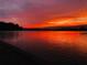 Scenic lake view with a red sunset reflecting vibrant orange and red colors on the water and neighborhood homes at 1110 Terralago Way, Kissimmee, FL 34746