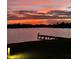 Scenic lake view with a lighted dock at sunset with clouds reflecting vibrant orange and red colors at 1110 Terralago Way, Kissimmee, FL 34746