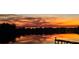 Scenic lake view with a dock at sunset reflecting vibrant orange and yellow colors from the sky and neighborhood homes at 1110 Terralago Way, Kissimmee, FL 34746