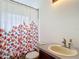 Cozy bathroom with floral shower curtain, sink, and standard toilet at 12445 Bohannon Blvd, Orlando, FL 32824