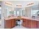 Spacious bathroom with double sinks, wooden cabinets, and large mirrors reflecting the shower at 12445 Bohannon Blvd, Orlando, FL 32824