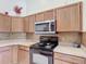 Well-maintained kitchen featuring wood cabinets, neutral countertops, and black appliances at 12445 Bohannon Blvd, Orlando, FL 32824