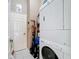 Practical laundry room with stacked washer and dryer, shelving for storage, and tiled floor at 12445 Bohannon Blvd, Orlando, FL 32824