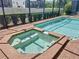 Close-up of octagonal hot tub with surrounding brick deck and a screened-in pool area at 1614 Lima Ave, Kissimmee, FL 34747