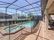 Screened-in pool and jacuzzi with brick patio, surrounded by a safety fence at 1614 Lima Ave, Kissimmee, FL 34747