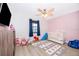 Bedroom with pink accent wall, wood-look floors, white crib, and play area at 1730 Carolyn Ct, St Cloud, FL 34769