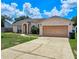 Charming single-story home featuring a well-maintained lawn and attached two-car garage at 215 Grovepark Dr, Davenport, FL 33837