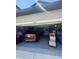 Garage area with gray epoxy floor, red KIA, and overhead storage at 2289 Seven Oaks Dr, St Cloud, FL 34772