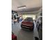 Garage with gray epoxy flooring, a red KIA, overhead garage door, and storage on either side at 2289 Seven Oaks Dr, St Cloud, FL 34772