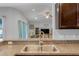 Kitchen sink with stone countertops overlooking the living room and ceiling fan at 233 E Cattail, Lake Alfred, FL 33850