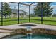 Relaxing hot tub with waterfall, nestled in a screened enclosure overlooking a green backyard at 2350 Bradbury Rd, Haines City, FL 33844