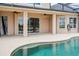 View of the covered lanai with ceiling fans, windows, and a beautiful pool with light turquoise water at 2350 Bradbury Rd, Haines City, FL 33844