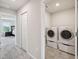 Conveniently located laundry room with tile flooring and modern, stacked washer and dryer units at 2462 Sweet Viburnum Way, Ocoee, FL 34761