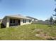 Backyard featuring lush green grass and the rear exterior of the home with a covered patio at 2569 Trinidad Rd, Haines City, FL 33844
