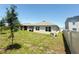 Well-kept backyard featuring green grass and the exterior of the home with trees and a fence at 2569 Trinidad Rd, Haines City, FL 33844