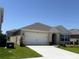 Single-story home with a neutral color scheme, well-maintained lawn, and an attached garage at 2569 Trinidad Rd, Haines City, FL 33844