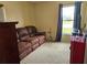 Cozy living room with a comfortable brown couch, a small glass table, and a window overlooking the outdoors at 307 Fox Loop, Davenport, FL 33837