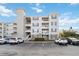 Three-story condo building featuring balconies, neutral siding, and a well-maintained parking area under a blue sky at 3175 Feltrim Pl # 101, Kissimmee, FL 34747