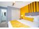Bedroom features a gray bed frame, yellow accent wall, and a view of the adjoining bathroom at 3181 Tocoa Cir, Kissimmee, FL 34746