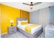 Comfortable bedroom with stylish gray furniture, a yellow accent wall, and a ceiling fan at 3181 Tocoa Cir, Kissimmee, FL 34746