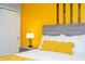 Cozy bedroom with gray wood-look bed frame, yellow accent wall, and decorative lamp on nightstand at 3181 Tocoa Cir, Kissimmee, FL 34746