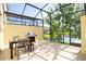 Screened-in patio with a dining table, grill, and a view of a serene pond at 3181 Tocoa Cir, Kissimmee, FL 34746
