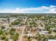 Expansive aerial view of neighborhood homes with mature trees, streets, and a distant lake under a beautiful blue sky at 320 S Seminole Ave, Lake Alfred, FL 33850