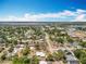 A beautiful aerial view of a residential neighborhood with homes surrounded by lush greenery and a distant lake under a blue sky at 320 S Seminole Ave, Lake Alfred, FL 33850