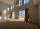 A view of the living room with high ceilings, neutral walls, and sliding doors to the backyard at 340 Cimarron Ct, Poinciana, FL 34759