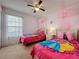 bedroom featuring 2 twin beds, a ceiling fan, a window, and pink canopies above each bed at 4707 Pershoie Ln, Kissimmee, FL 34746