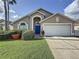 Charming single-Gathering home featuring a manicured lawn, a two-car garage and a bright blue front door at 4707 Pershoie Ln, Kissimmee, FL 34746