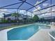 Enclosed pool area featuring lounge chairs, greenery, and a view of the sky at 4707 Pershoie Ln, Kissimmee, FL 34746