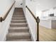 Carpeted staircase with white railing and wood banister leading to an open-concept living space at 6501 Cyrils Dr, St Cloud, FL 34771