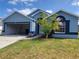 Charming blue home featuring an attached garage, well-kept lawn, and appealing landscaping at 664 Eagle Pointe S, Kissimmee, FL 34746
