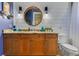Stylish bathroom featuring granite countertop, wooden cabinet, and round mirror at 6761 Valhalla Way, Windermere, FL 34786