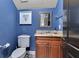 Stylish half bathroom featuring blue walls, a wood vanity, and elegant tile flooring at 6761 Valhalla Way, Windermere, FL 34786