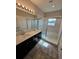 Bathroom with dual sinks, granite countertops, and a glass-enclosed shower at 7673 Ripplepointe Way, Windermere, FL 34786