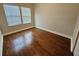 A bedroom with hardwood floors and natural lighting from two windows with wooden blinds at 7673 Ripplepointe Way, Windermere, FL 34786
