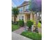 Charming two-story townhome featuring lush landscaping, a brick walkway, and a welcoming covered porch at 7673 Ripplepointe Way, Windermere, FL 34786