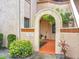 Inviting condo entrance with stucco archway, mature landscaping, terracotta-colored walkway, and tile accents at 7865 Sugar View Ct # 7865, Orlando, FL 32819