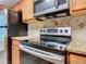 Close-up of kitchen appliances, including stainless steel range and microwave, paired with granite countertops and wood cabinets at 7865 Sugar View Ct # 7865, Orlando, FL 32819