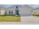 Charming single-Gathering home featuring a well-manicured lawn, blue door, and attached two-car garage at 824 Ofanto Way, Haines City, FL 33844