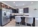 Modern kitchen boasts stainless steel appliances, dark cabinets, quartz countertops, and a central island with seating at 824 Ofanto Way, Haines City, FL 33844