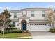 Beautiful two-story white home featuring a blue front door, two-car garage, and manicured landscaping at 9020 Stinger Dr, Davenport, FL 33896